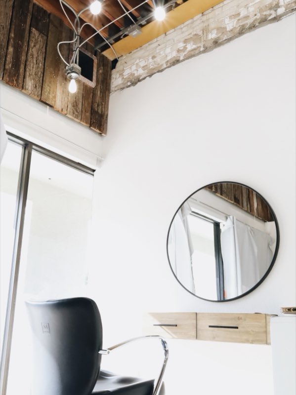 Styling station with a round mirror, reclaimed wood and exposed brick